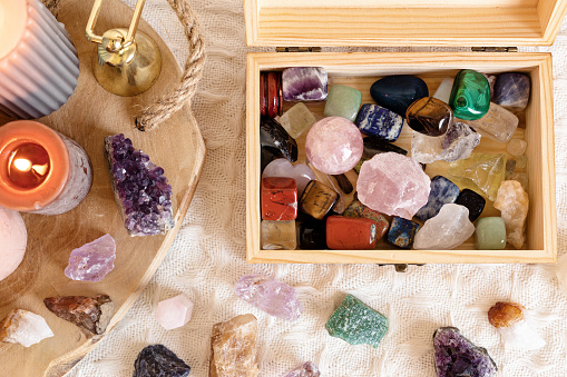 This is a photo of a variety of crystals including an angel aura quartz tower, rose quartz, and a rhodonite palm stone.
