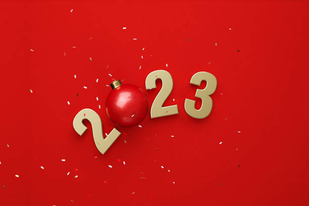 istock Gold Colored 2023 And Red Christmas Bauble Forming 2023 Beneath Falling Confetti Over Red Background 1439872423
