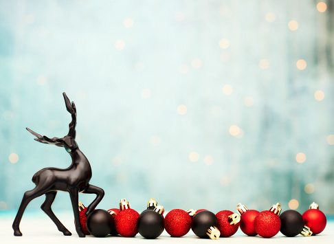 Modern Christmas background with deer and vibrant red and black Christmas decorations. Space for text
