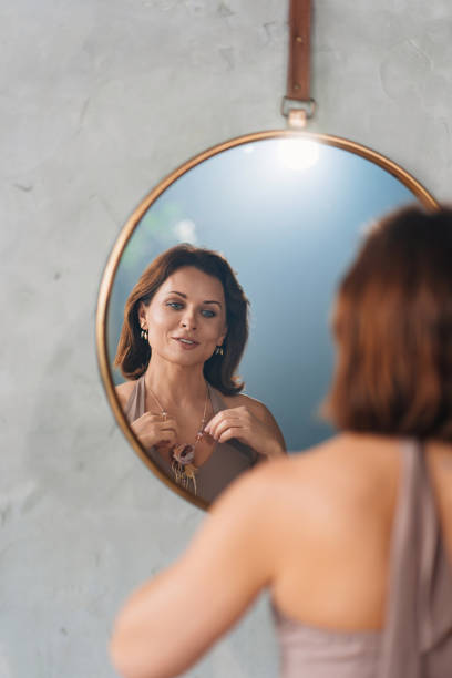 istock an attractive woman admires her reflection in a round mirror. 1439877223