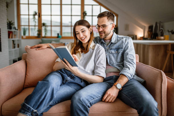 istock Young couple reading book together at home 1439879065