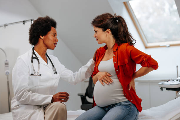 Doctor advising pregnant woman at hospital. stock photo