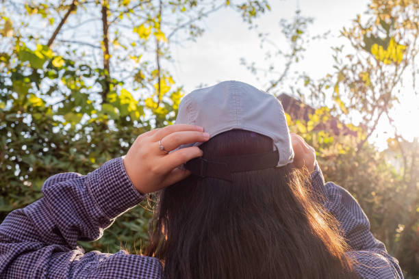 une jeune femme eurasienne ajuste son chapeau dans la cour, journée d’automne ensoleillée - district of north vancouver photos et images de collection