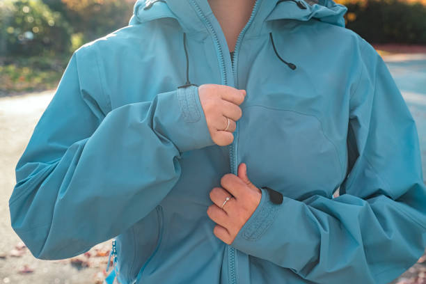 giovane donna multirazziale che si chiude giacca a vento blu, giorno d'autunno - giacca a vento foto e immagini stock