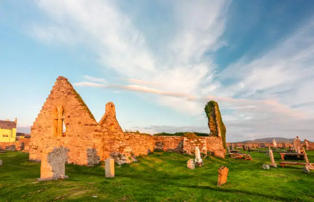 Magical historic landmark near Durness,founded 8th Century,important Celtic monastery,ancient gravestones and graveyard,grass covered,dramatic sunset sky,at Balnakeil Bay,eerie atmosphere at dusk.