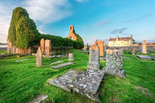 Magical historic landmark near Durness,founded 8th Century,important Celtic monastery,ancient gravestones and graveyard,grass covered,dramatic sunset sky,at Balnakeil Bay,eerie atmosphere at dusk.