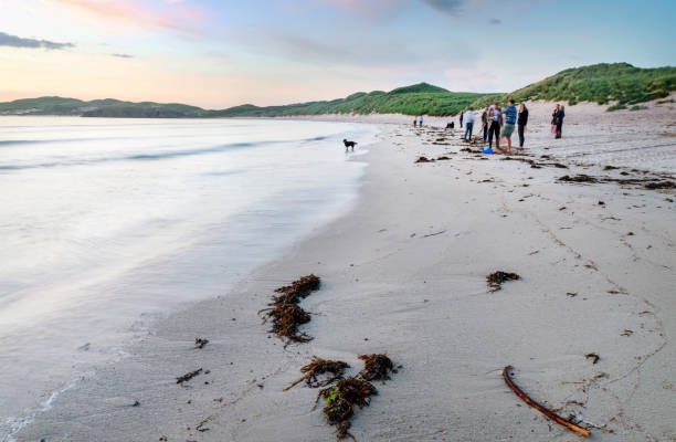Young people gather on Balnakeil beach to celebrate the mid summer setting sun. Balnakeil,Northwest Scotland-July 28 2022: Folks traveling Scotland,enjoy the late sunset and warm mid-summer weather,socializing with beer,music and a campfire,on the fine sands of the remote bay. beach fire scotland stock pictures, royalty-free photos & images