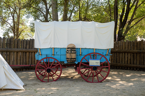Genoa, NV. Overnight canvas tent beside a blue Prairie Schooner wagon with red wheels at the Mormon Station Historic Park.