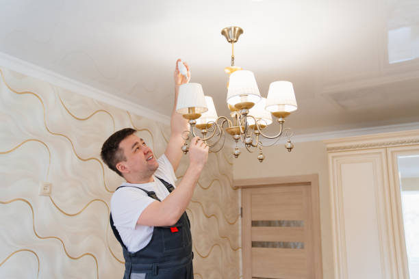 istock A male electrician changes the light bulbs in the ceiling light. 1439896743