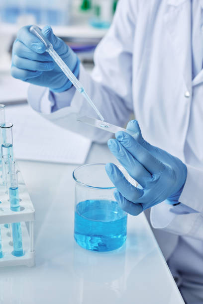 istock Gloved researcher adding several drops of liquid substance on small glass 1439900373