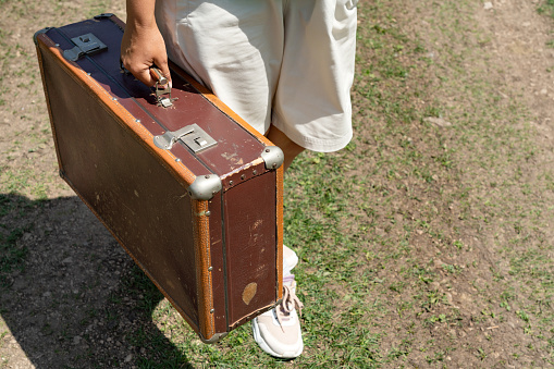 Girl holding an old leather suitcase in her hands