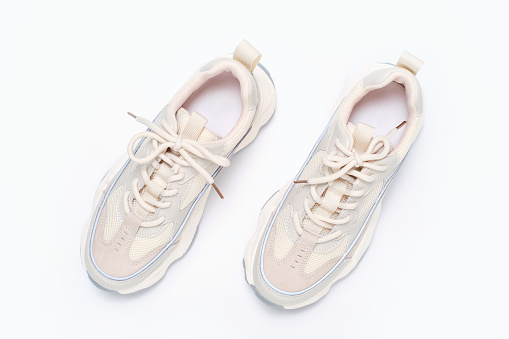 White sneakers isolated. Close-up of a pair white elegant stylish leather sport shoes isolated on a white background. Clipping path. Kids shoe fashion. Modern design footwear for workout. Macro.