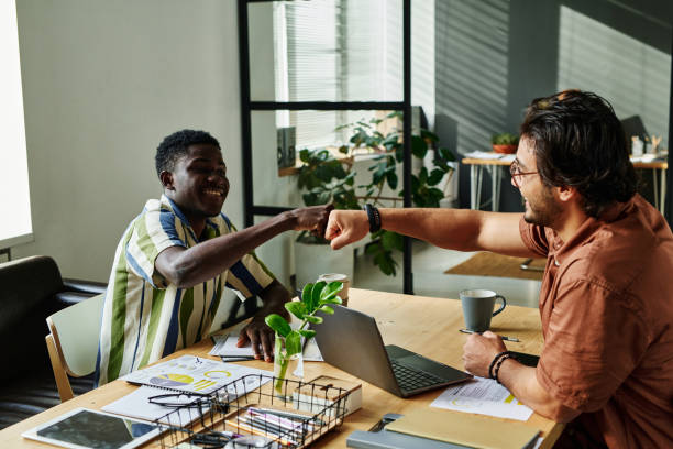 istock Two happy young intercultural colleagues making punch bump 1439911889