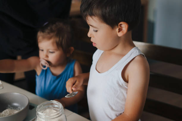 istock Close-up view of two kids adjusting kitchen scale for weighing ingredients, while preparing homemade cake. Food concept. Family activity concept. Love people concept. Happy family, childhood. Family lifestyle concept. Fun family. 1439912064