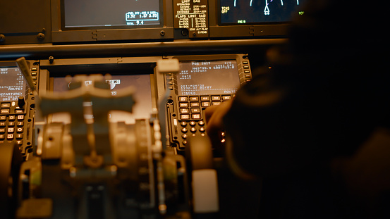 Male copilot inserting flight coordinates to arrive at destination, using dashboard command for navigation. Control panel power buttons and aviation compass, flying aircraft. Close up.