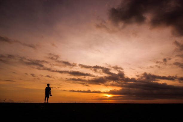istock silhouette of man standing on the beach with sunset light 1439914245