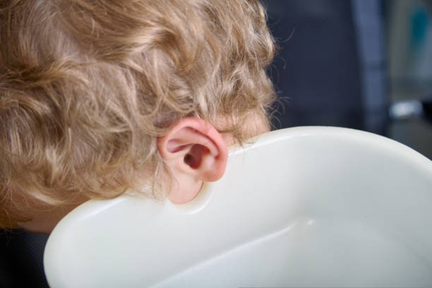 child's head tilted onto a water tank while rinsing the ears in the hospital Close-up of a child's head tilted onto a water tank while rinsing the ears in the hospital. The child is prepared for a painless procedure of washing the auricles at the ENT flushing water stock pictures, royalty-free photos & images