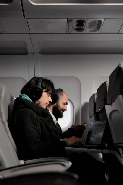 istock Man and woman using laptop and smartphone on airplane flight 1439915962