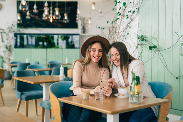 istock women friends using mobile phone on coffee break in cafeteria 1439915984