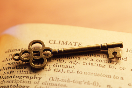 An old key rests on top of the definition of the word climate in an old dictionary.
