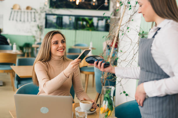 istock woman paying contactless with mobile phone in cafe 1439916019