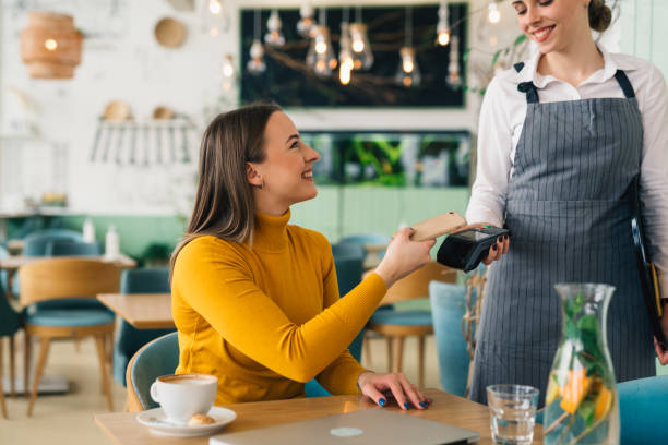 istock woman paying contactless with mobile phone in cafe 1439916028