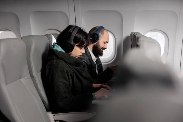 istock Young travellers using laptop and smartphone on airplane flight 1439917454