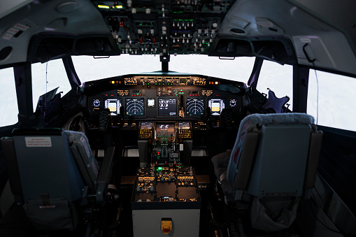 Nobody in captain cockpit with power engine lever to fly airplane, using dashboard command buttons and control panel navigation. Windscreen and radar compass handle, airline travel.