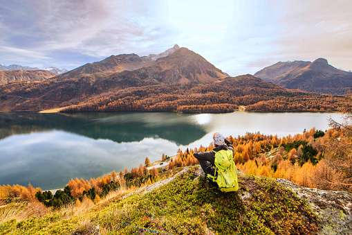 Man contemplates autumn landscape in a mountain lake