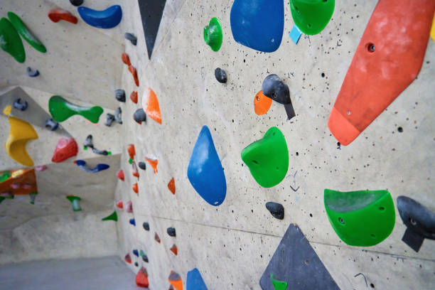 Bouldering gym with artificial colourful rock wall Wall for bouldering in gym with holds for climbing. Active extreme sport concept crag stock pictures, royalty-free photos & images