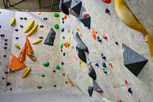 Wall for bouldering in gym with holds for climbing. Active extreme sport concept