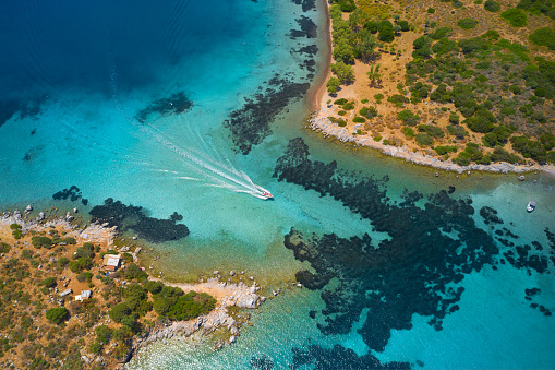 Aerial view of blue sea and speed boat sailing along the mediterranean coast. Landscape of turkish riviera nature