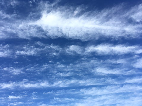 Wispy clouds in a bright blue sky with a feather shape