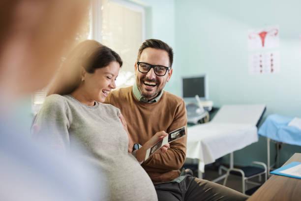 That's our baby honey! Happy pregnant couple received an ultrasound scan at gynecologists' office. human fertility stock pictures, royalty-free photos & images