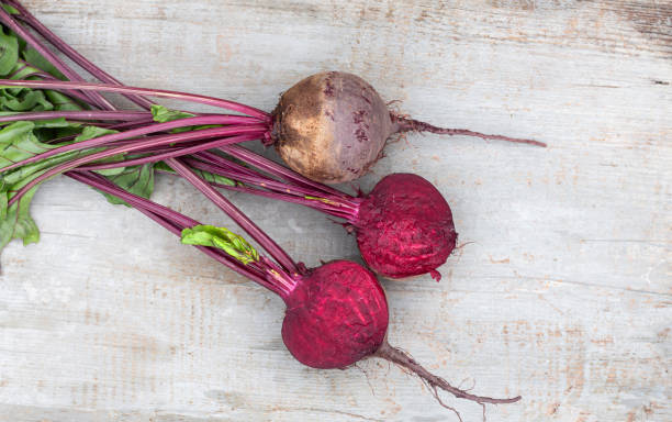 istock washed red beets with tops, cut in half, put on a wooden countertop.top view 1439939029