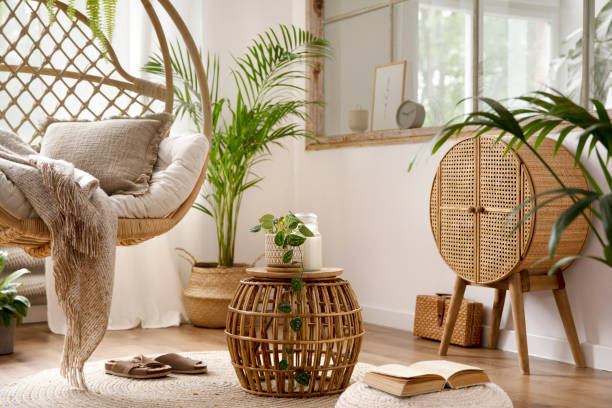 istock Interior design of boho living room interior with hanging swing, window, plants, commode and wooden bench. Beige carpet with brown slippers. Home decor. Template. 1439939194