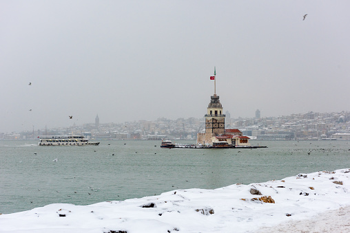 Snowy day in Uskudar. View of Maiden's Tower with seagulls in Uskudar, Istanbul, Turkey.