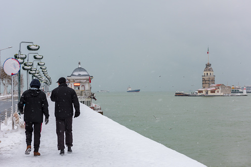 Snowy day in Uskudar. View of Maiden's Tower with seagulls in Uskudar, Istanbul, Turkey.