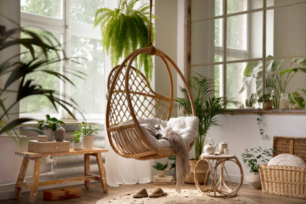 istock Creative composition of living room interior with hanging swing, window, plants, round coffee table, braided carpet, wooden bench and personal accessories. Home decor. Template. 1439939823