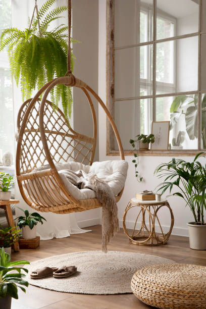 innenarchitektur der boho-komposition mit hängender schaukel, pflanzen, fenster, rundem couchtisch, hocker, büchern, pflanzen in blumentöpfen und persönlichen accessoires. wohnkultur. schablone. - showcase interior home decorating architecture home interior stock-fotos und bilder