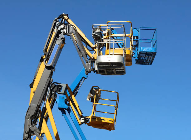 istock Black, blue and yellow aerial work platforms against cloudless blue sky 1439943058
