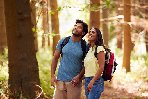 Couple With Backpacks Hiking Or Walking Through Woodland Countryside