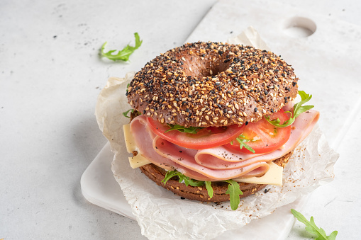 bagel filled with rocket, turkey ham, cream cheese and tomato