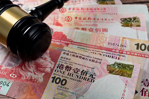 Gavel on stack of Hong Kong currency.