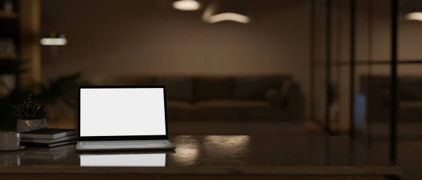 istock Modern workspace with laptop mockup and copy space over blurred dark living room 1439948040
