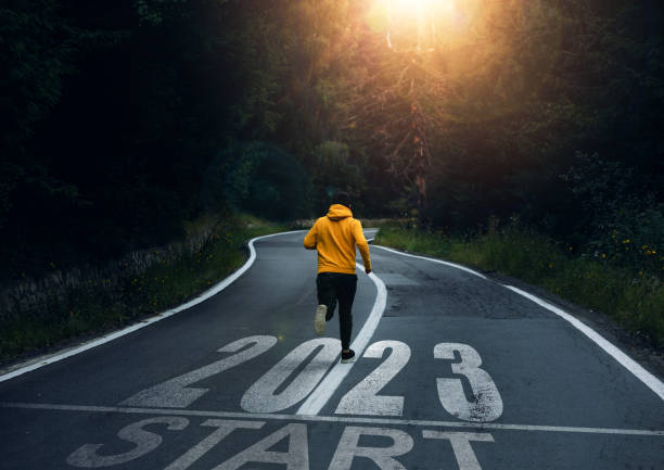 Man running on the mountain road towards new goals in 2023. New Year 2023 with new ambitions, challenge, plans, goals and visions. stock photo