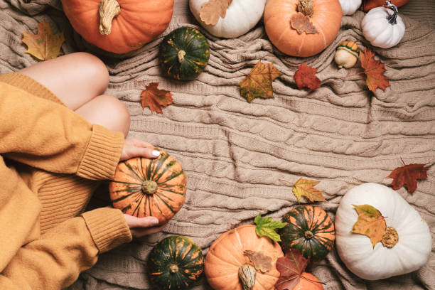 istock woman sitting between pumpkins 1439948197