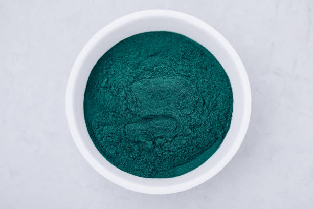 スピルリナ。グレイの石の背景に緑藻粉末クロレラ、ボウルのスピルリナ - chlorella spirulina bacterium algae nutritional supplement ストックフォトと画像