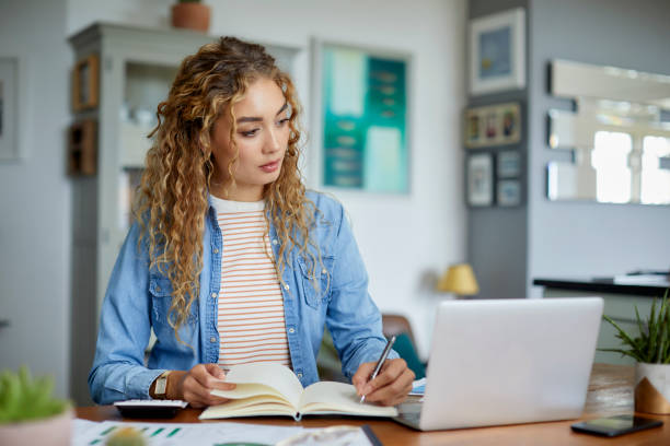 istock Businesswoman writing in diary sitting at table 1439949141