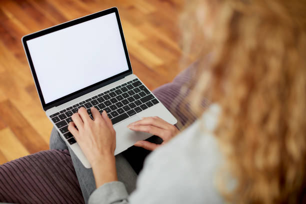 istock Woman using laptop with blank screen relaxing on sofa 1439949464